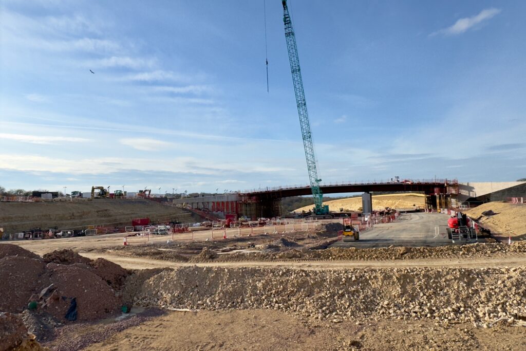 Construction site with two wide carriageways and a bridge, all partially completed.